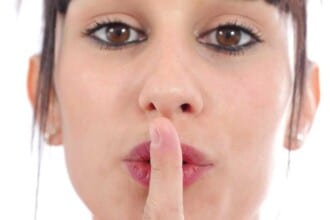 close up portrait young woman with finger lips against white background