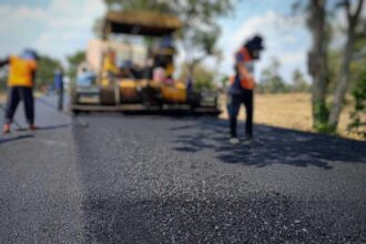 Manual workers paving asphalt on road