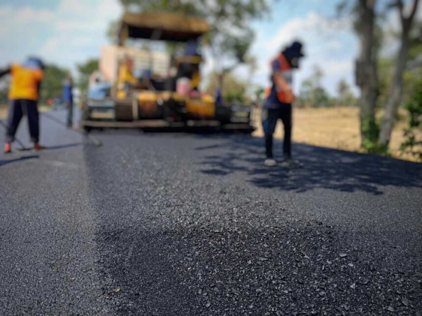 Manual workers paving asphalt on road