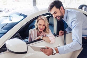 Salesman talking with female client sitting in the car