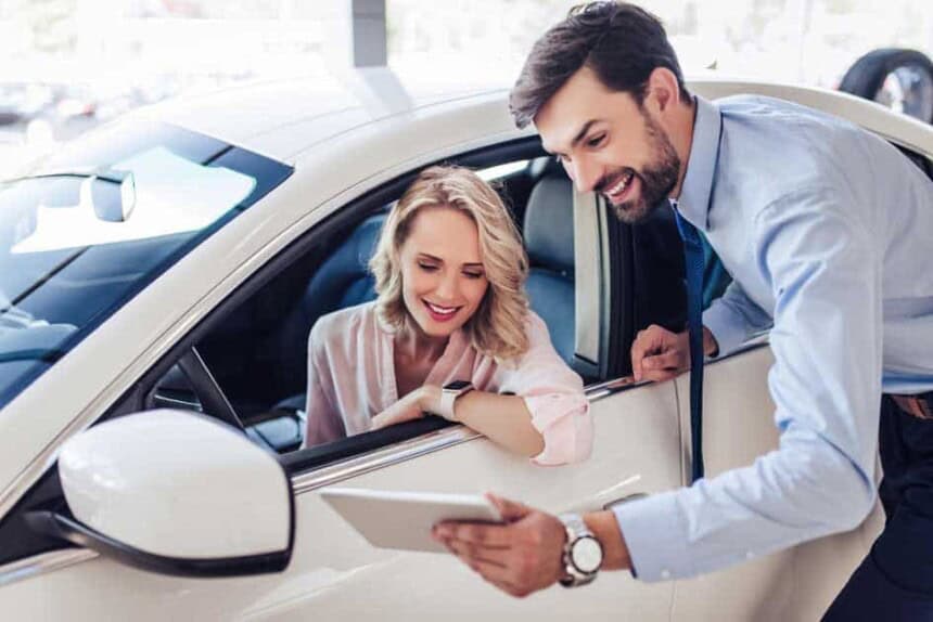 Salesman talking with female client sitting in the car