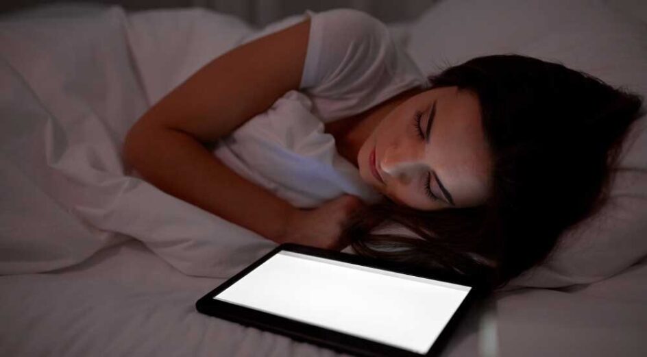 Woman with tablet pc sleeping in bed at night