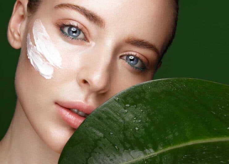 beautiful fresh girl with cosmetic cream face natural makeup green leaves beauty face