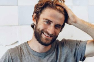 close up portrait young bearded man standing against grunge weathered wall