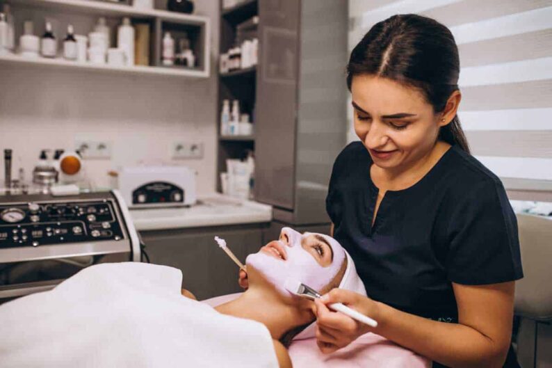 cosmetologist applying mask face client beauty salon
