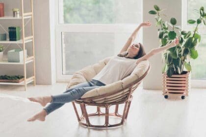 full length photo pretty young lady sit wicker armchair stretch arms wear casual style clothes house apartment