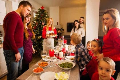 group best friends gathered together christmas dinner young parents their kids standing around table full delicious food housewife holding plate with main course