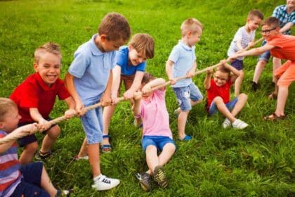 group happy little children are playing tug war outside grass