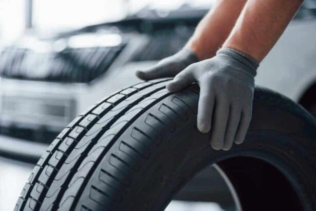 hands only mechanic holding tire repair garage replacement winter summer tires