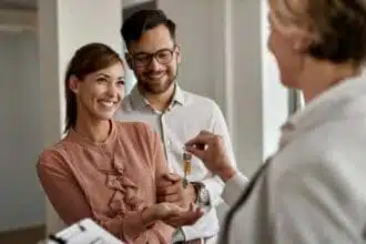 happy couple buying their new home receiving keys from real estate agent