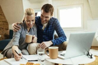 happy couple writing notes while going through home finances during their coffee time