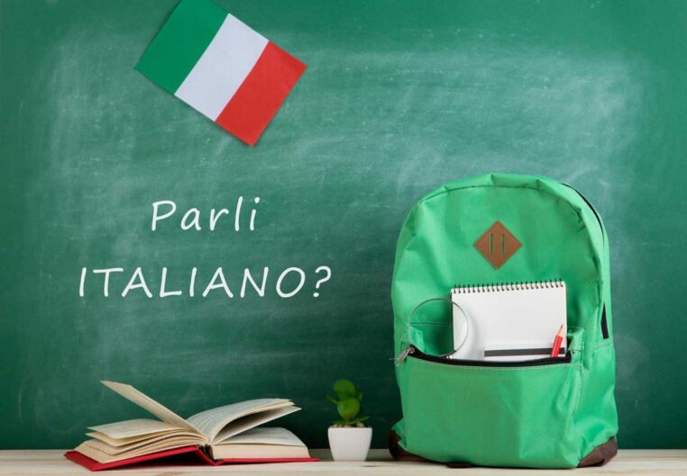 learning languages concept green backpack blackboard with text parli italiano flag italy books notebooks