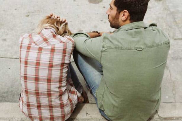 man and woman sitting on sidewalk 226166