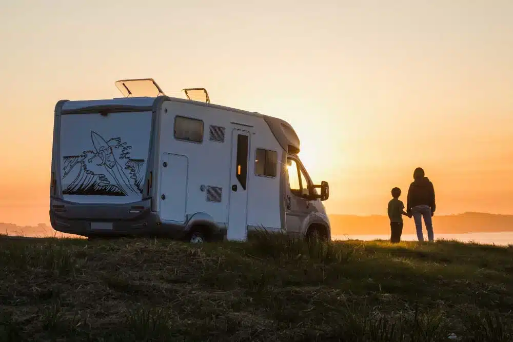 mother son watching sunset with their motor home edge sea