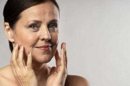 older woman with make up posing with hands face copy space