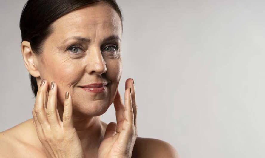 older woman with make up posing with hands face copy space