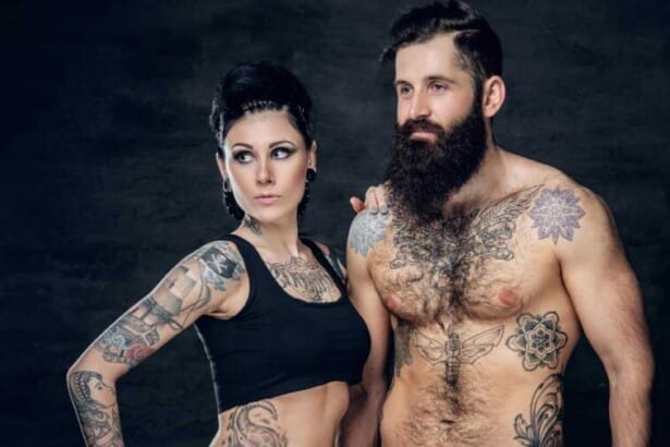 portrait shirtless tattooed bearded hipster male brunette female with tattoo ink her torso dark grey background 1