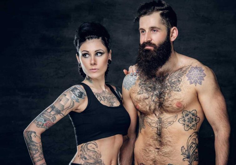 portrait shirtless tattooed bearded hipster male brunette female with tattoo ink her torso dark grey background 1