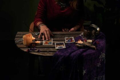 pythoness reads tarot cards table with candles