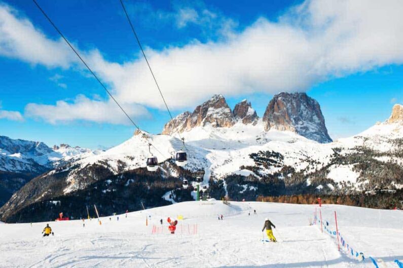 skiers skiing down slope ski resort winter dolomite alps val di fassa italy