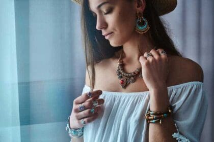 stylish brunette boho chic woman wears white blouse straw hat with big earrings bracelets golden necklace silver rings fashionable hippie gypsy bohemian outfit with jewelry details