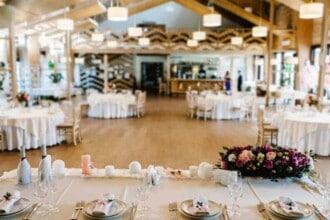 view restaurant hall festive table decorated composition flowers greenery candles wedding banquet hall table newlyweds covered with tablecloth served with dishes cutlery close up