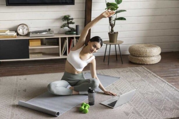 young asian fitness girl doing stretching sport workout home stretch arms looking laptop f