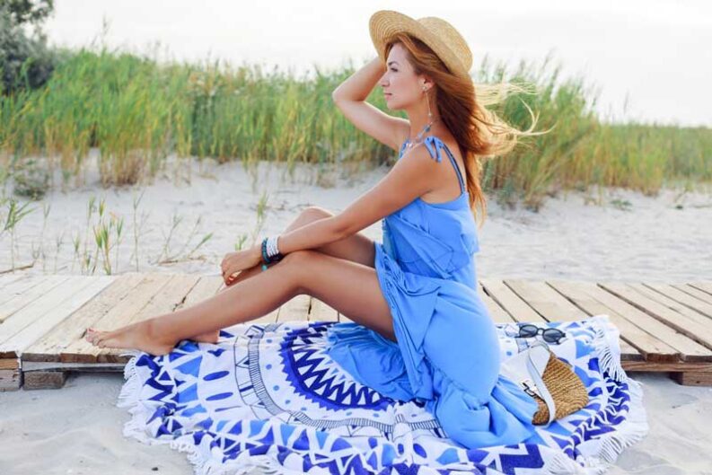 woman in straw hat relaxing on sunny beach in blue dress original 1