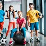 Laughing preteen kids posing with sport equipment